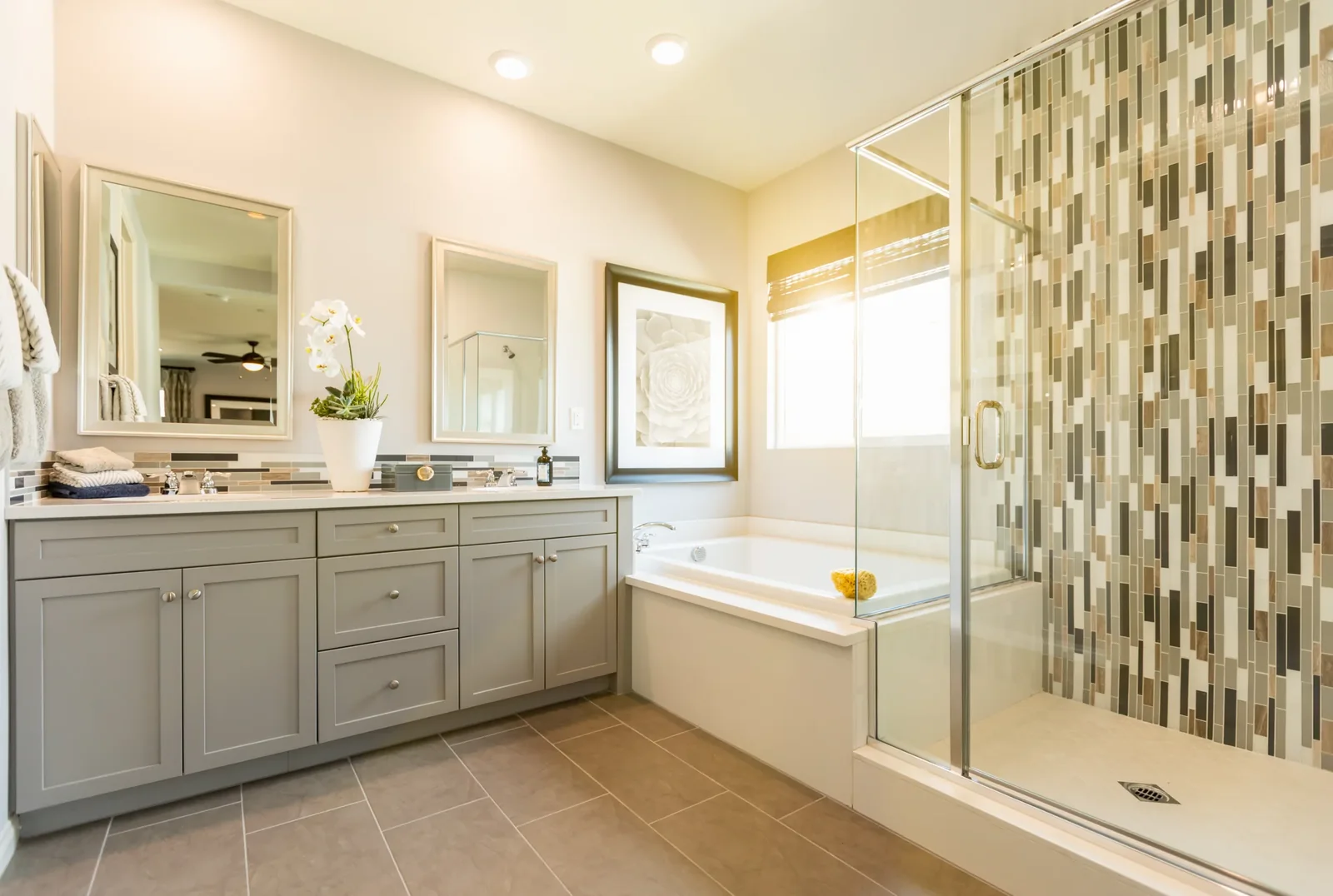 Bathroom with a double sink vanity, a drop in tub and a glass shower with mosaic tile