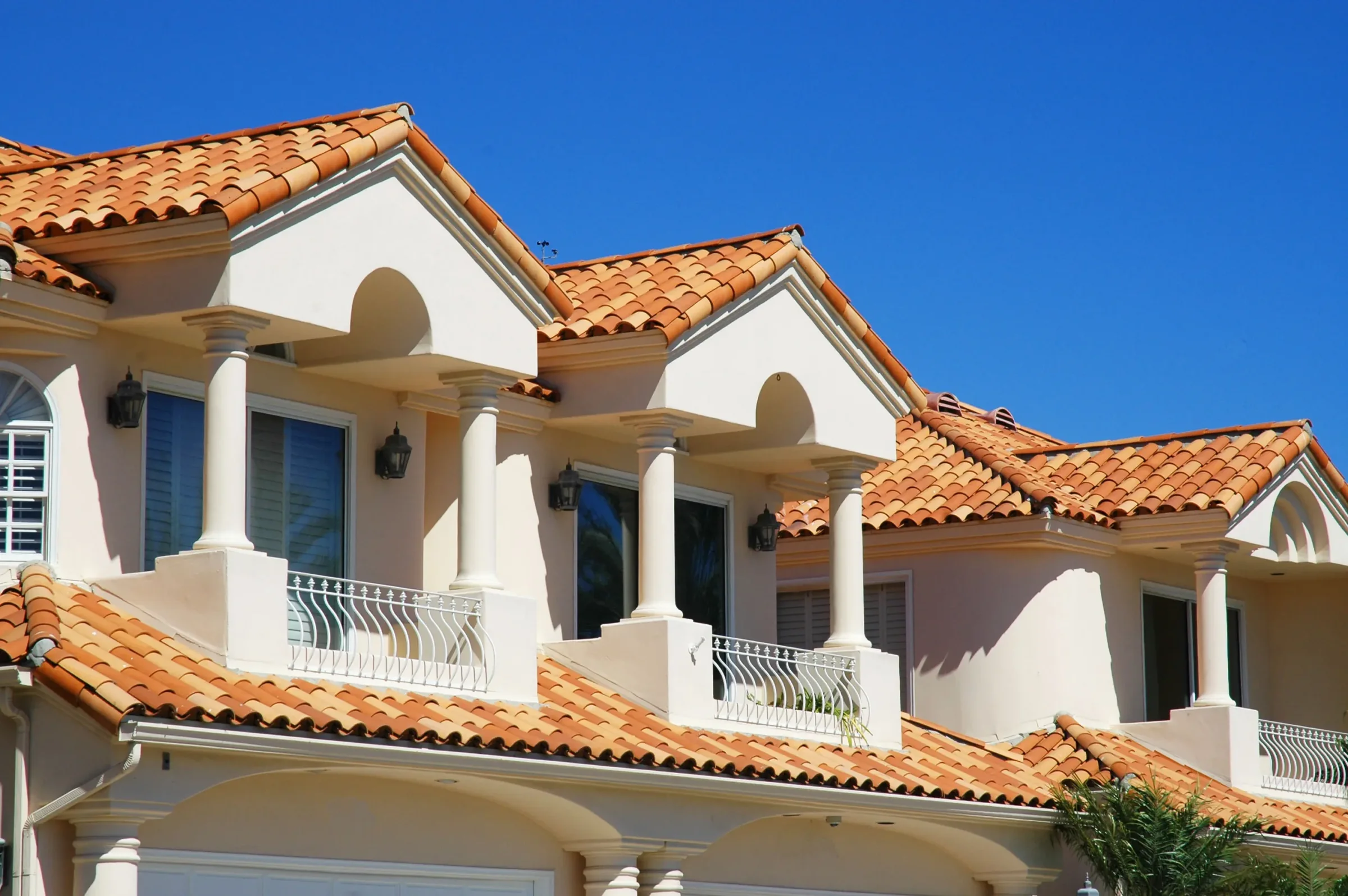 Terracotta barrel tile roofs on a row of Southern California homes under a clear sky